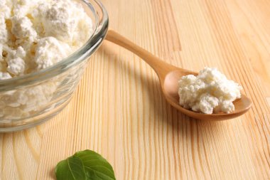 ahşap arka plan üzerinde bir cam kase süzme peynir