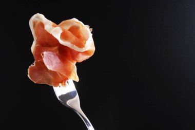 Prosciutto, jamon çatal karanlık bir arka plan üzerinde
