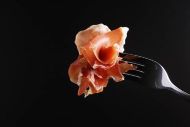 Prosciutto, jamon çatal karanlık bir arka plan üzerinde