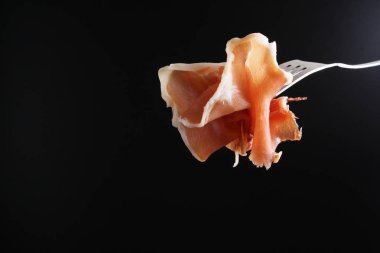 Prosciutto, jamon çatal karanlık bir arka plan üzerinde