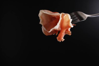 Prosciutto, jamon çatal karanlık bir arka plan üzerinde