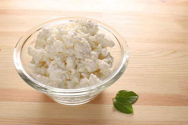 ahşap arka plan üzerinde bir cam kase süzme peynir