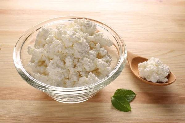 ahşap arka plan üzerinde bir cam kase süzme peynir