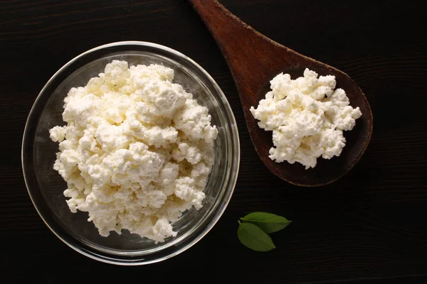 karanlık bir arka plan üzerinde bir cam kase süzme peynir