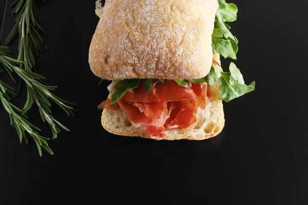 Sandwich prosciutto hamon ciabatta a dark background — Stock Photo, Image