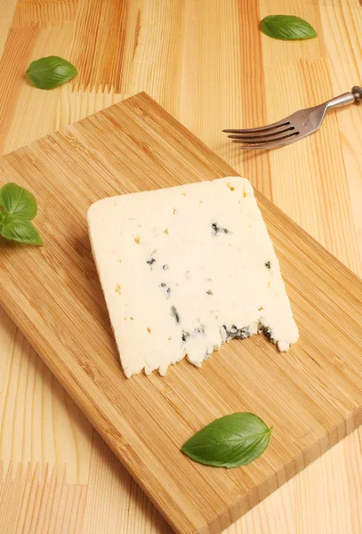 Plísňový sýr na dřevěném prkénku s bazalkou — Stock fotografie