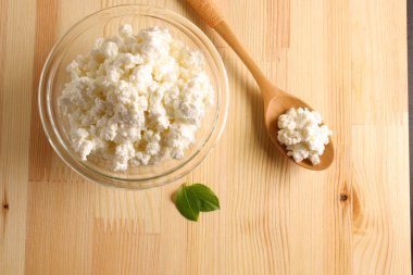 ahşap arka plan üzerinde bir cam kase süzme peynir