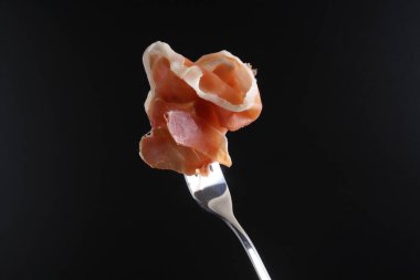 Prosciutto, jamon çatal karanlık bir arka plan üzerinde