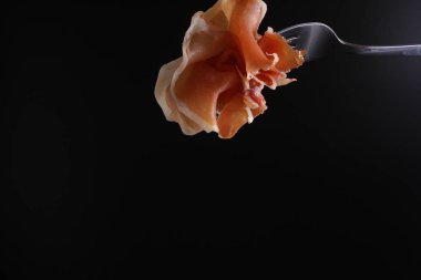 Prosciutto, jamon çatal karanlık bir arka plan üzerinde