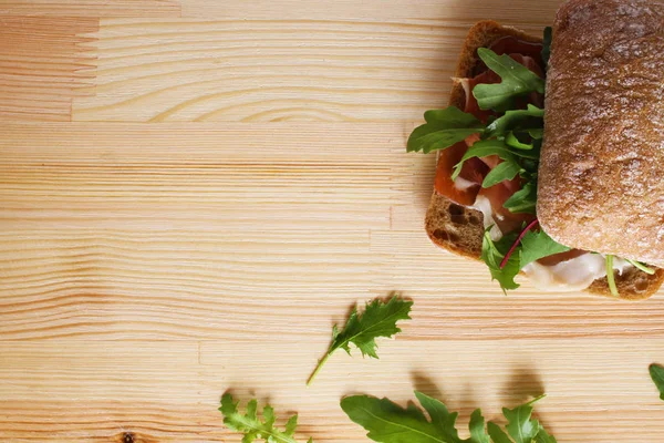 Sanduíche prosciutto hamon ciabatta em um fundo de madeira — Fotografia de Stock