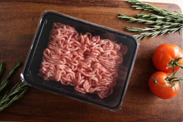 Carne picada na embalagem em um fundo de madeira — Fotografia de Stock