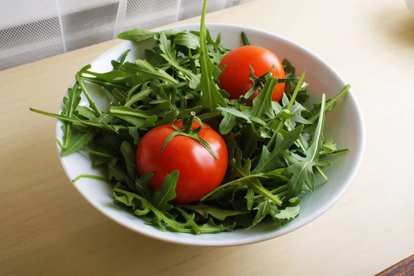 Salad of rucola tomato on a wooden background — Stock Photo, Image