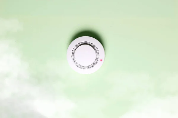 緑の光を背景にした火災警報センサー — ストック写真