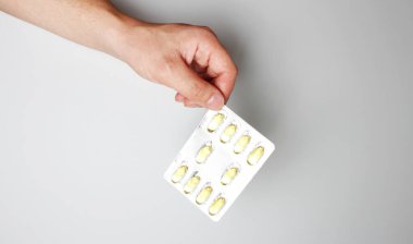 hafif bir arka plan üzerinde elinde kapsül blister