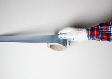 İnşaat bandı gümüş eldivenli el.