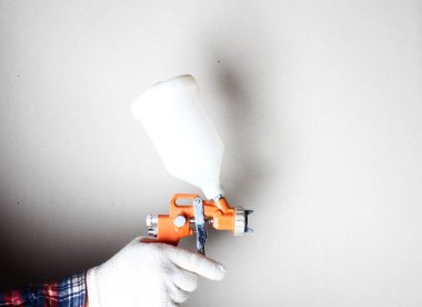 hafif arkaplanda eldiven içinde turuncu boya fırçası