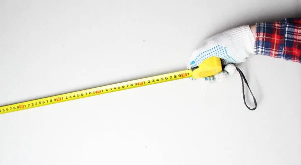 yellow tape measure in hand construction glove