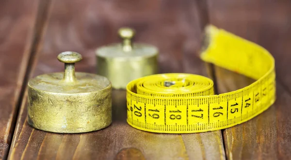 Weight loss, diet concept, tape measure and rustic metal weights — Stock Photo, Image
