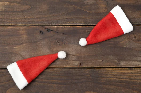 コピースペースと木製の背景に2つのクリスマスのサンタの帽子 — ストック写真
