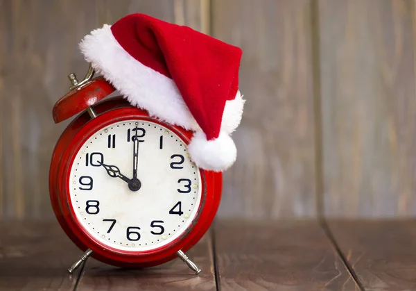 クリスマスの時間のコンセプト、木製のバ上の赤いサンタの帽子目覚まし時計 — ストック写真