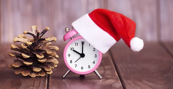 贈り物にクリスマスの時間。ピンクのサンタ目覚まし時計と松の木のコン — ストック写真