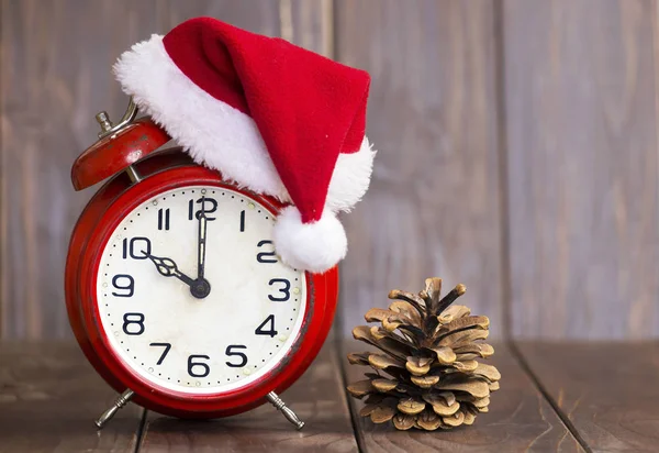 クリスマスだ赤いサンタの帽子目覚まし時計と松の木のコーン — ストック写真