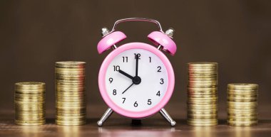 Zarif kahverengi arka planda altın sikkeler ve çalar saat, zaman para kavramı. Kopyalama alanı olan web pankartı.