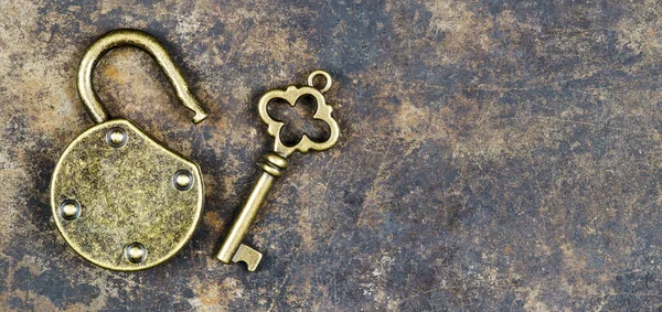Escape room concept. Web banner of a vintage golden key and unlocked padlock on a rusty metal background