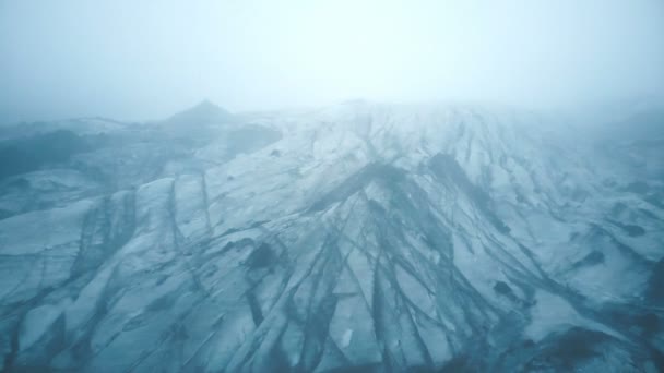 在云雾中飞过冰山的白色冰河 冰原上撒满了黑灰的海鸥的鸟瞰图 — 图库视频影像