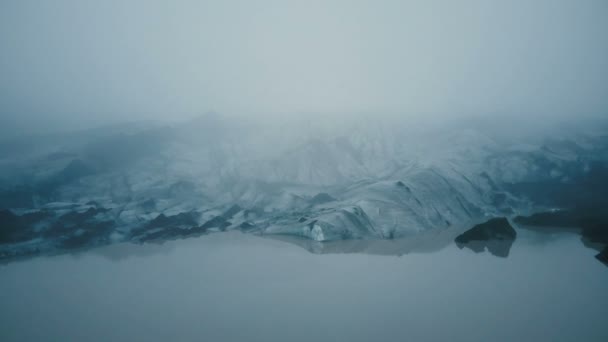 山の霧の中のアイスランドの永遠の氷の中で黒い灰と白い氷河Myrdalsjokullの空中ビュー — ストック動画