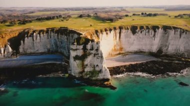 İHA gök mavisi deniz kıyısının üzerinde uçuyor ve günbatımı güneşinde etretat Normandiya yakınlarında destansı beyaz tebeşir yamacında.