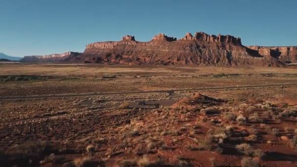 无人驾驶飞机在干旱的沙漠上空低空飞行 平坦的高山接近银色小型货车 靠近小公路 — 图库视频影像