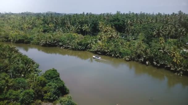 在丛林荒原上沿着美丽的热带雨林河流航行的白色小游船之后 无人驾驶飞机向左转 — 图库视频影像