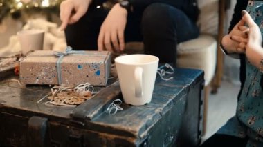 Masada oturup çay içen ve birbirlerine Noel hediyeleri veren genç çiftin yakın görüntüsü.