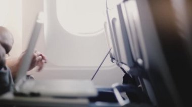 Uçuş sırasında çeşitli mobil cihazlar, akıllı telefonlar ve ekran laptopları kullanan yolcuların yan görüntülerini kapat