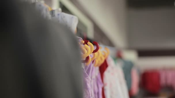 Verschiedene Kleidungsstücke Auf Kleiderbügeln Einem Geschäft Schieberegler Erschossen — Stockvideo