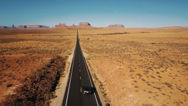 記念碑の谷ウサのアメリカの砂岩砂漠高速道路に沿って運転銀車の素晴らしい空中ショット — ストック動画