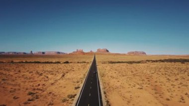 Drone gümüş renkli araba Arizona ve Utah anıtlar Vadisi'nde ünlü güneşli Amerikan çöl Otoban yol boyunca sürüş izler