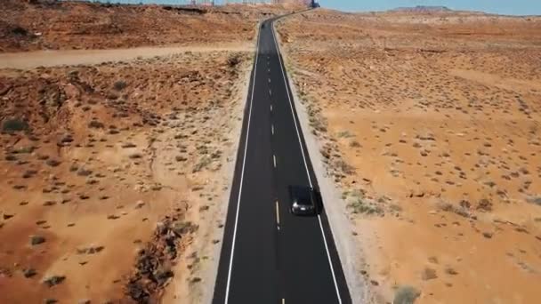 アリゾナ州の空の砂漠の高速道路の道路の銀車の後にドローンは平らな風景とスカイラインを明らかにするために傾きます — ストック動画