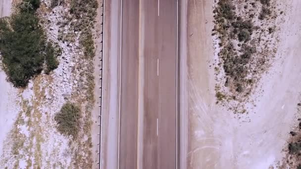 砂岩の砂漠の真ん中で美しい高速道路の道路カメラによって起こって白いトラックの拡大平面図ドローン — ストック動画