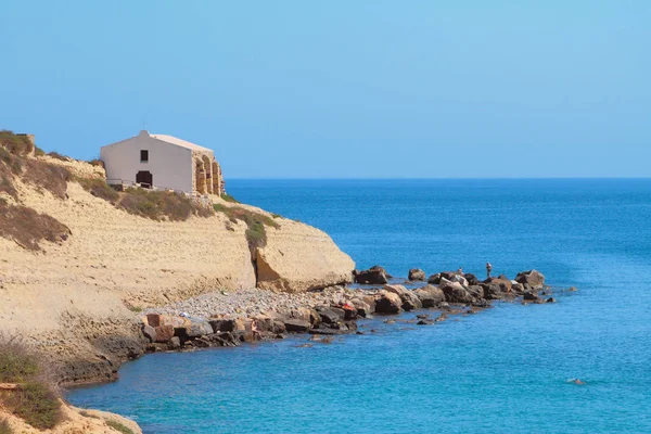 Deniz, kayalık sahil ve kilise. Porto Torres, İtalya