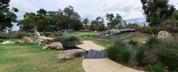 Joondalup'ta yürüyüş yolu, bahçeler ve su akıntısının panoramik manzarası