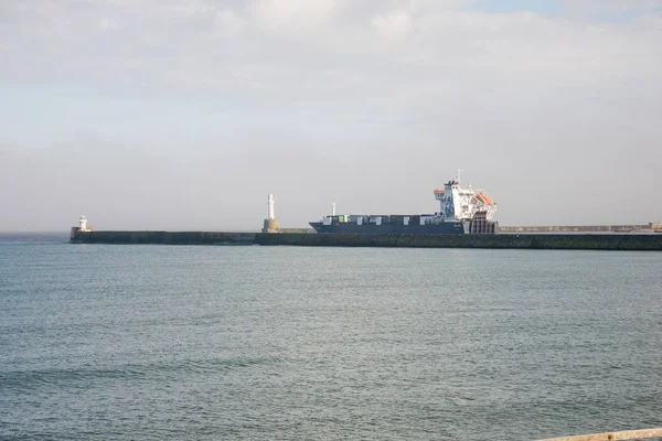 Ένα φορτηγό πλοίο αναχωρεί λιμάνι Aberdeen μεταξύ δύο φάρους λιμάνι εισόδου — Φωτογραφία Αρχείου
