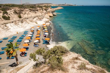 Larnaka Bölgesi, Kıbrıs, Temmuz-2017: birkaç şezlong ve şemsiye ile Kalymnos küçük bir plaj