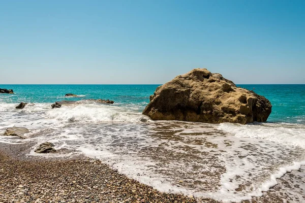 Velký kámen, obklopený vodou na oblázkové pláži Pissouri, Kypr — Stock fotografie