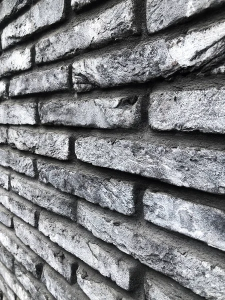 Alçak noktadan çekilen gri tuğlalı bir duvar. Bakış açısına giren çok sayıda tuğlanın dokusu. Tuğla gri bina. Böyle bir tuğla iç mekanda kullanılabilir.