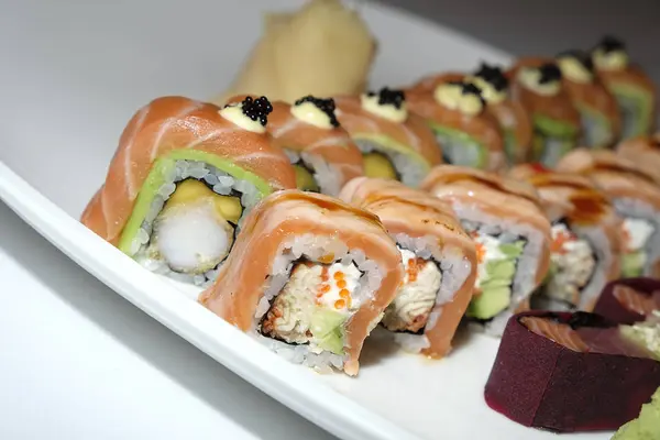Parlak bir ışıkta tabağa serilmiş lezzetli taze suşi. Japon yemeği. Büyük suşi parçaları güzel bir tabağa serilmiş ve beyaz üzerine izole edilmiş.