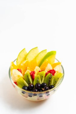 Beyaz arka planda şeffaf cam tabakta meyve salatası. Beyaz arka planda izole edilmiş taze meyve salatası.
