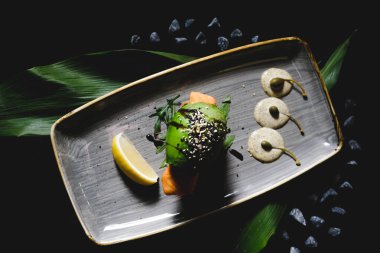 Siyah arka planda vejetaryen avokado burger, fast food, hamburger. Gri tabakta servis edilen somonlu büyük vejetaryen burger.