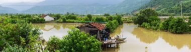 House among field near river in rain water season clipart